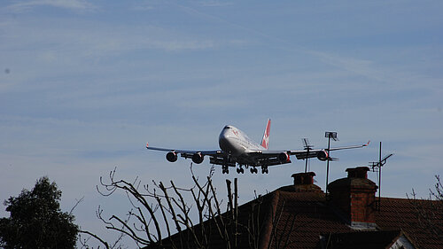 A plane flying close to houses.