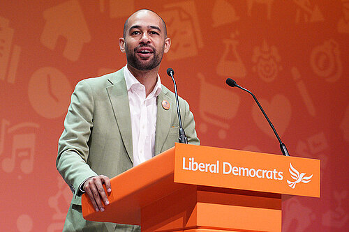 Josh Babarinde MP stands at a lecturn at Conference delivering a speech